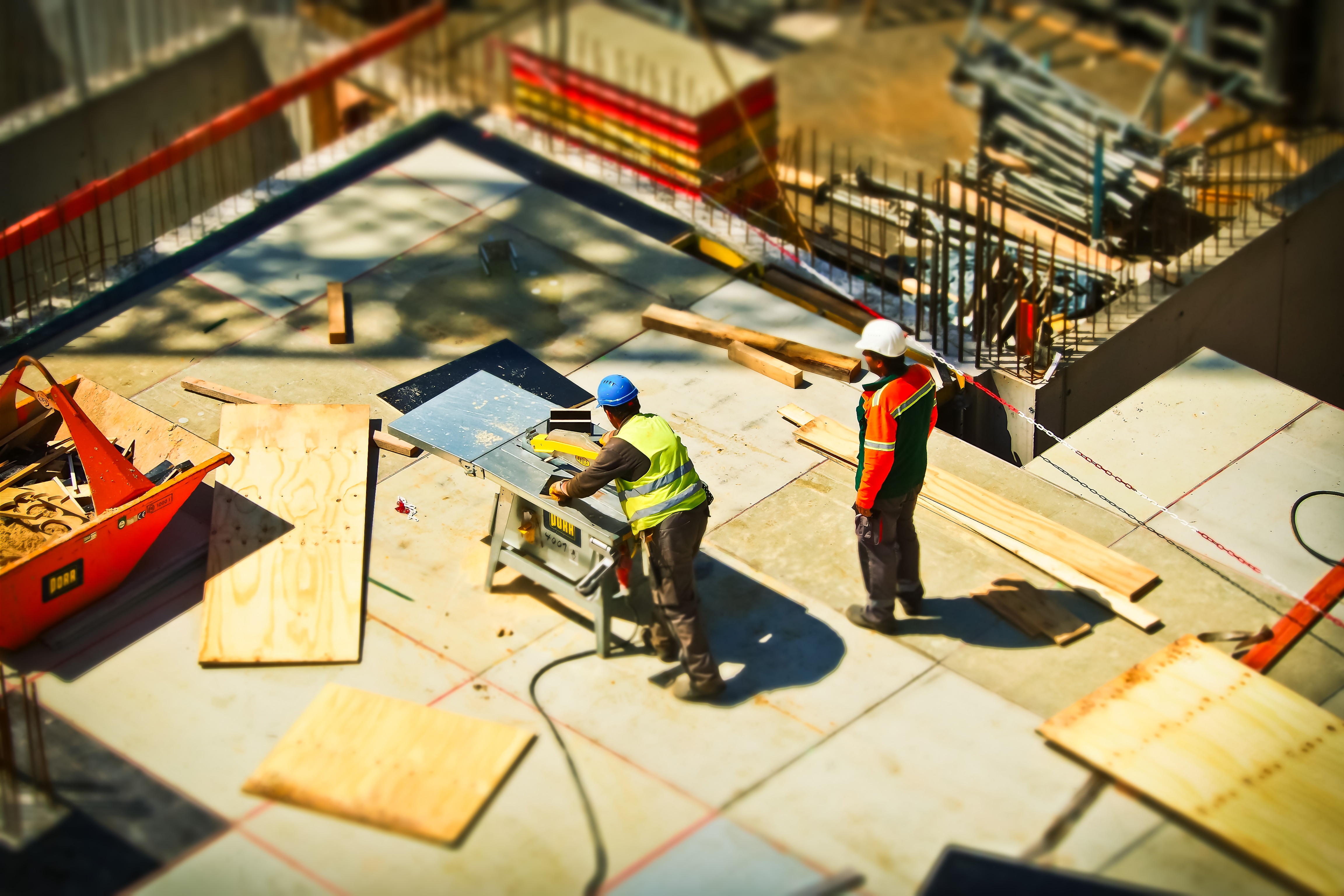 two construction workers cutting wood and pouring concrete for commercial construction